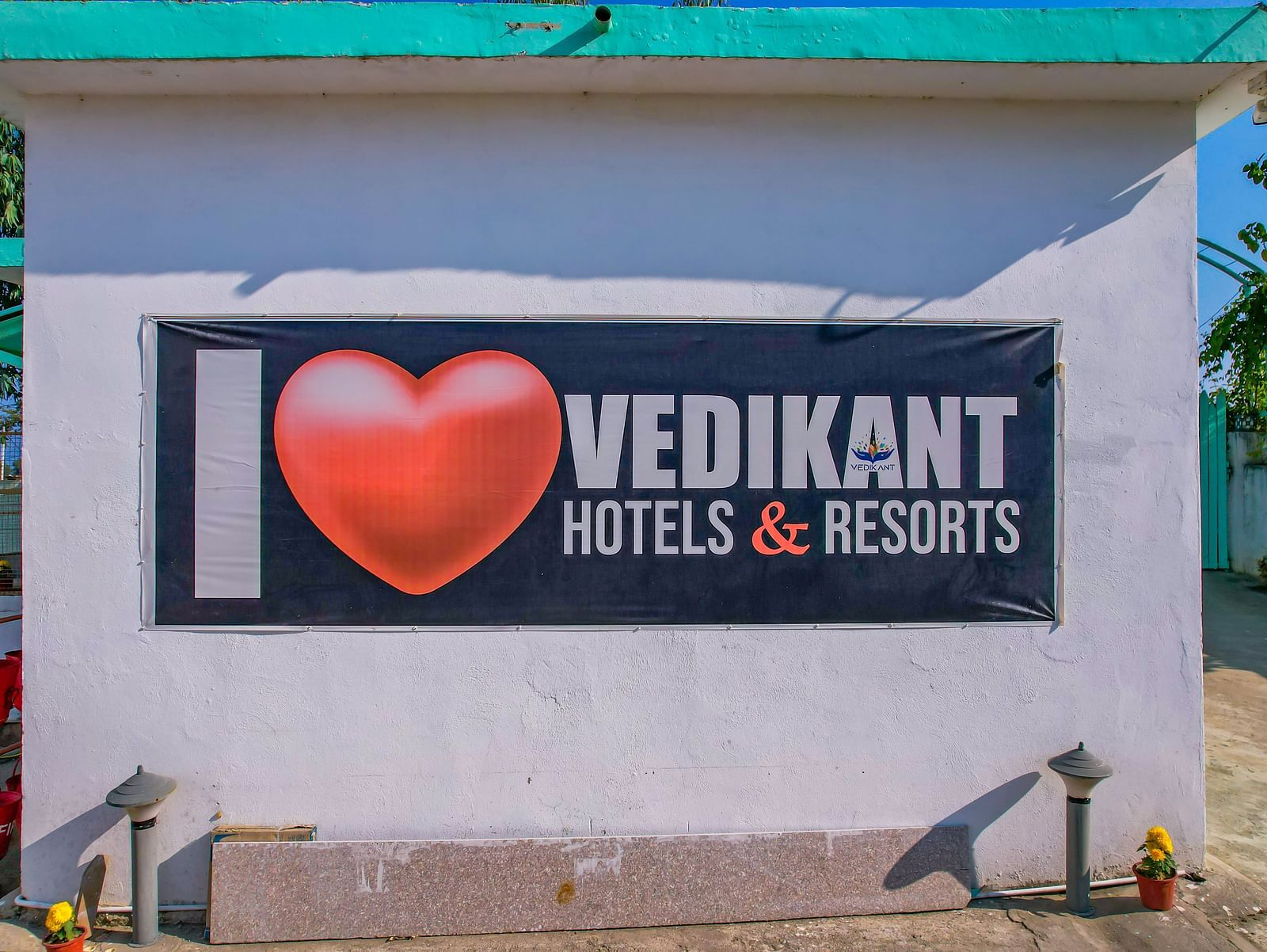 A large wall at Vedikant Resorts The Mallard Corbett featuring the 'I Love Vedikant Hotels & Resorts' signage with a paved area in front.