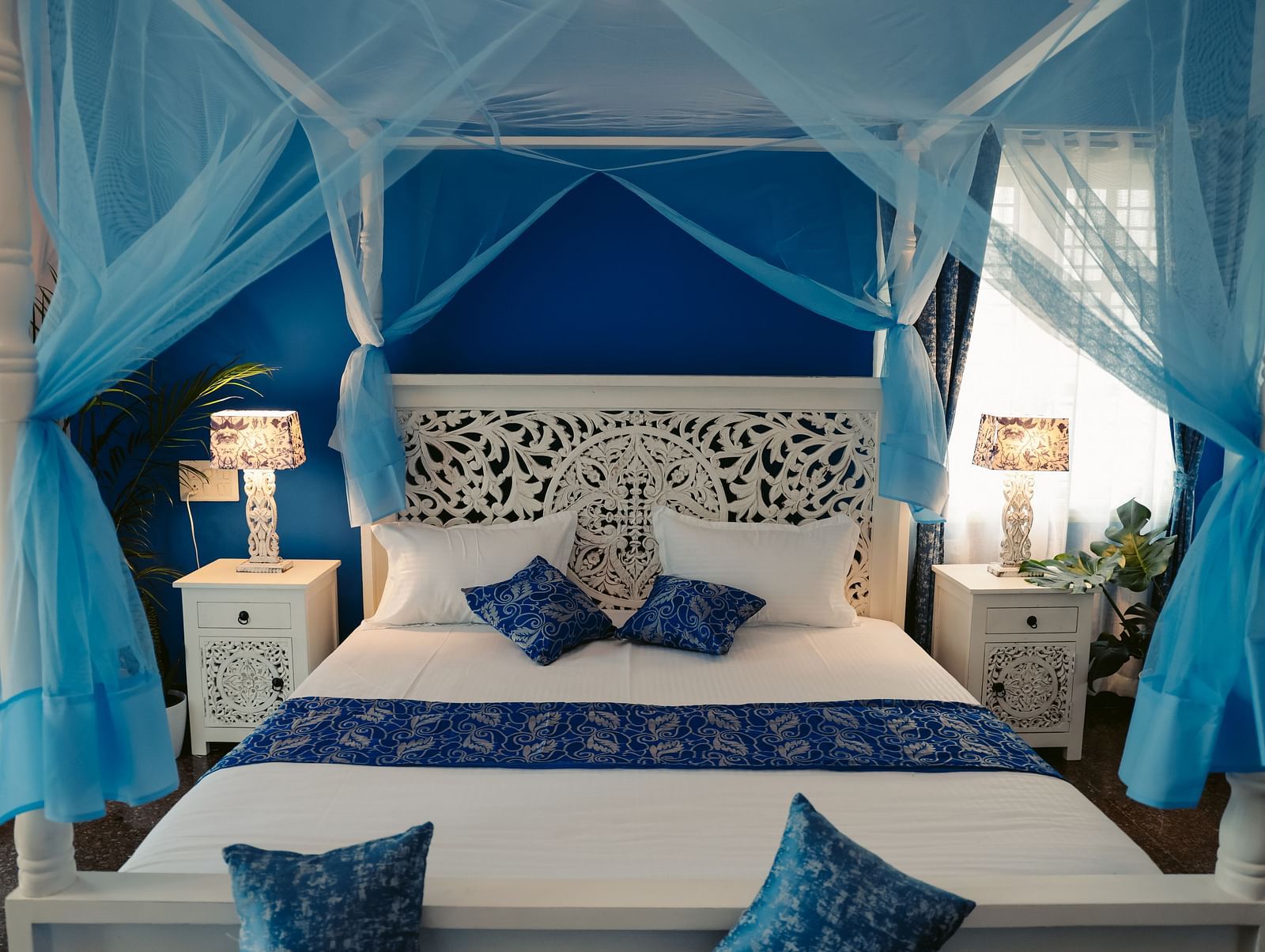 A bedroom with a white four-poster bed draped in sheer blue fabric | Adhyaya Heritage Reverbed