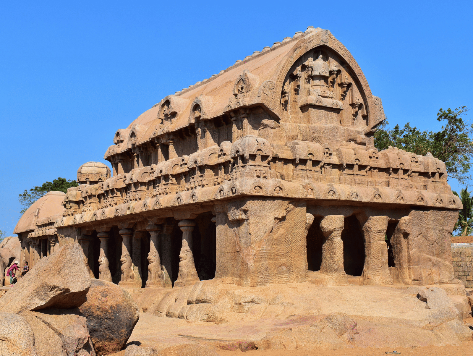 An ancient temple is made of large stones, with a blue sky in the background.