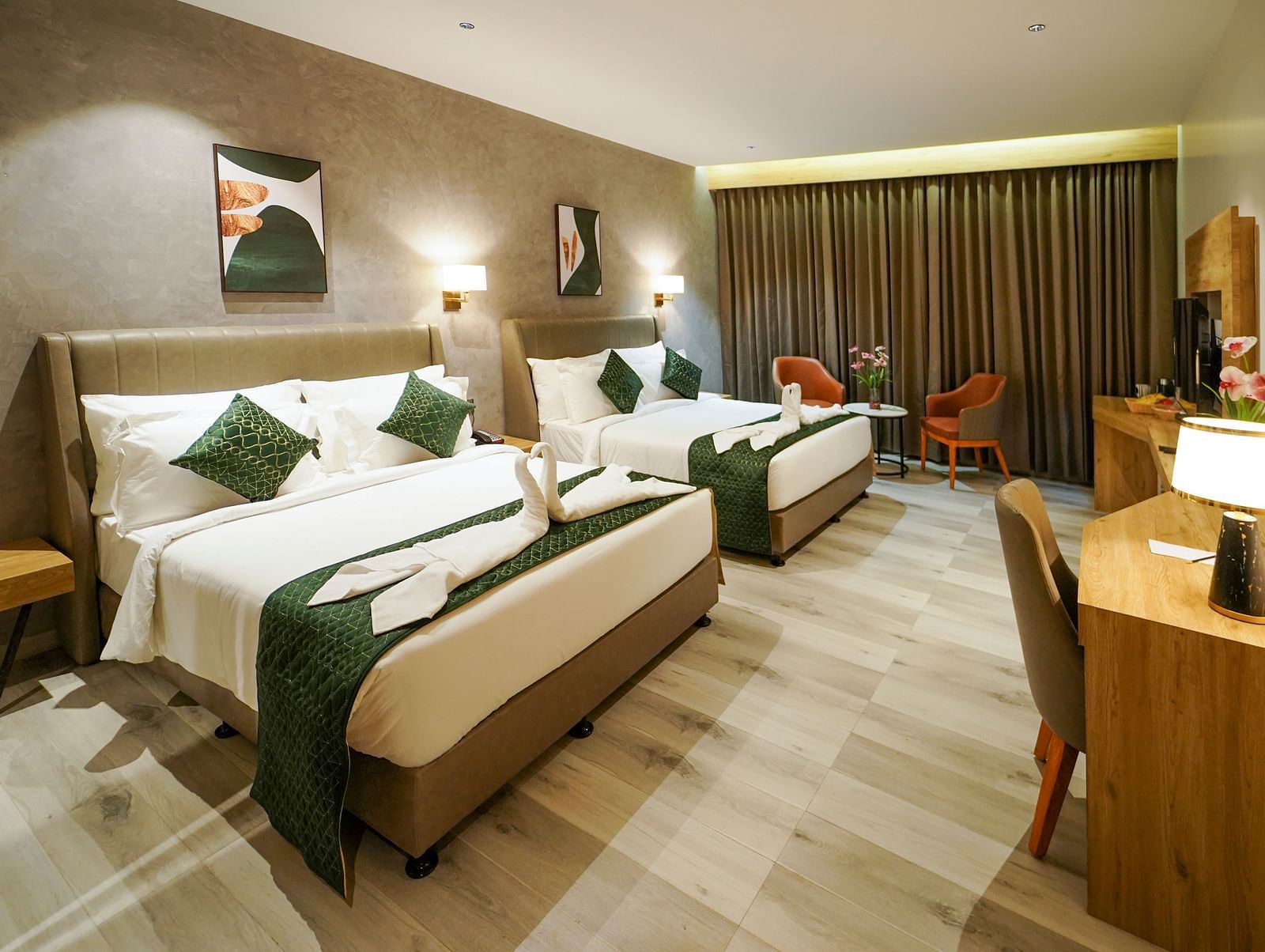 A hotel room features two beds with decorative linens, pillows, a desk area with a lamp and chair, and window curtains - Hotel Park Inn, Nellore.