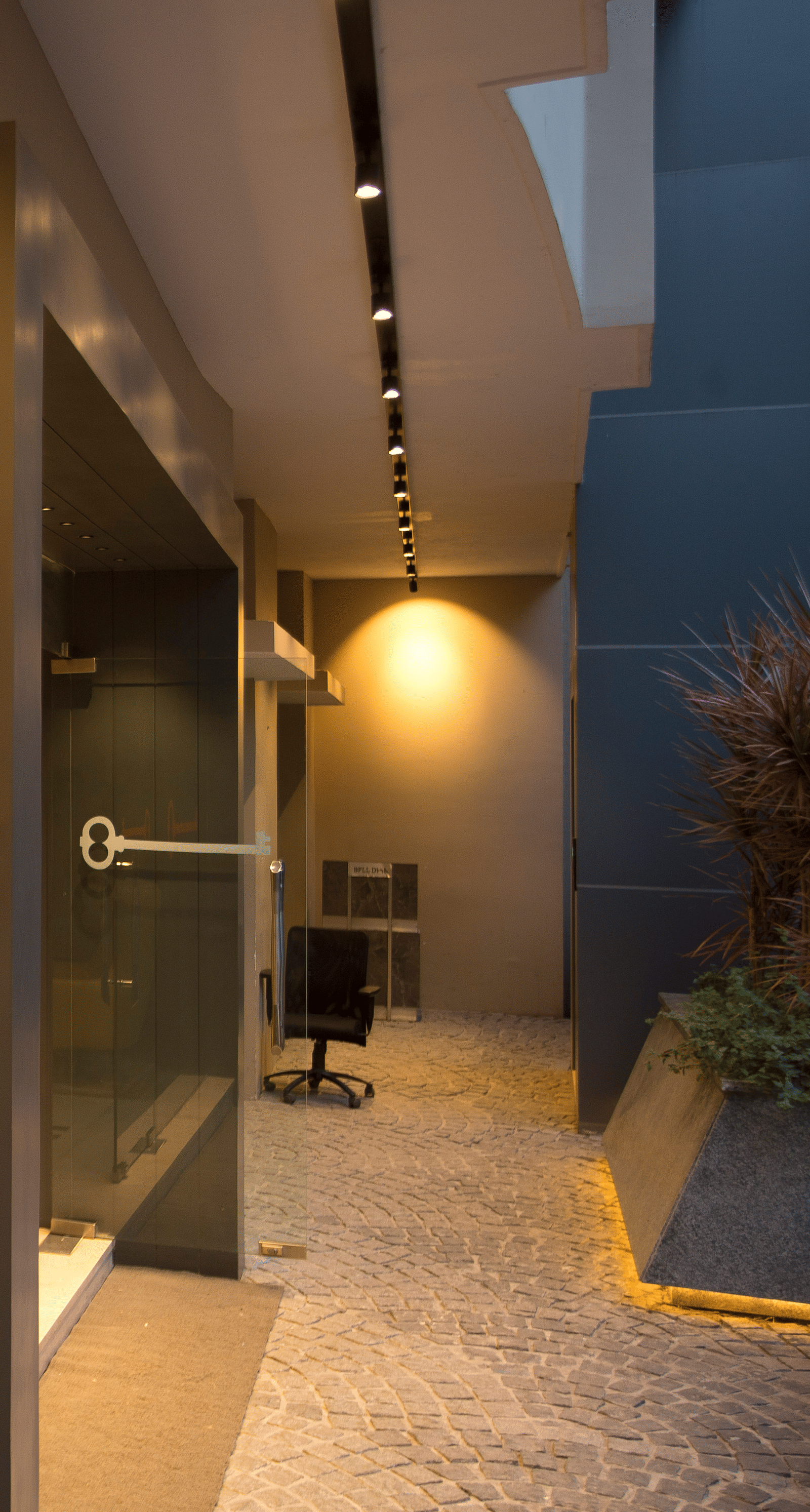 A sleek reception area featuring a curved red desk, a black chair and chic lighting against a panelled wall - Hotel Langford Keys by TGI, Shanti Nagar