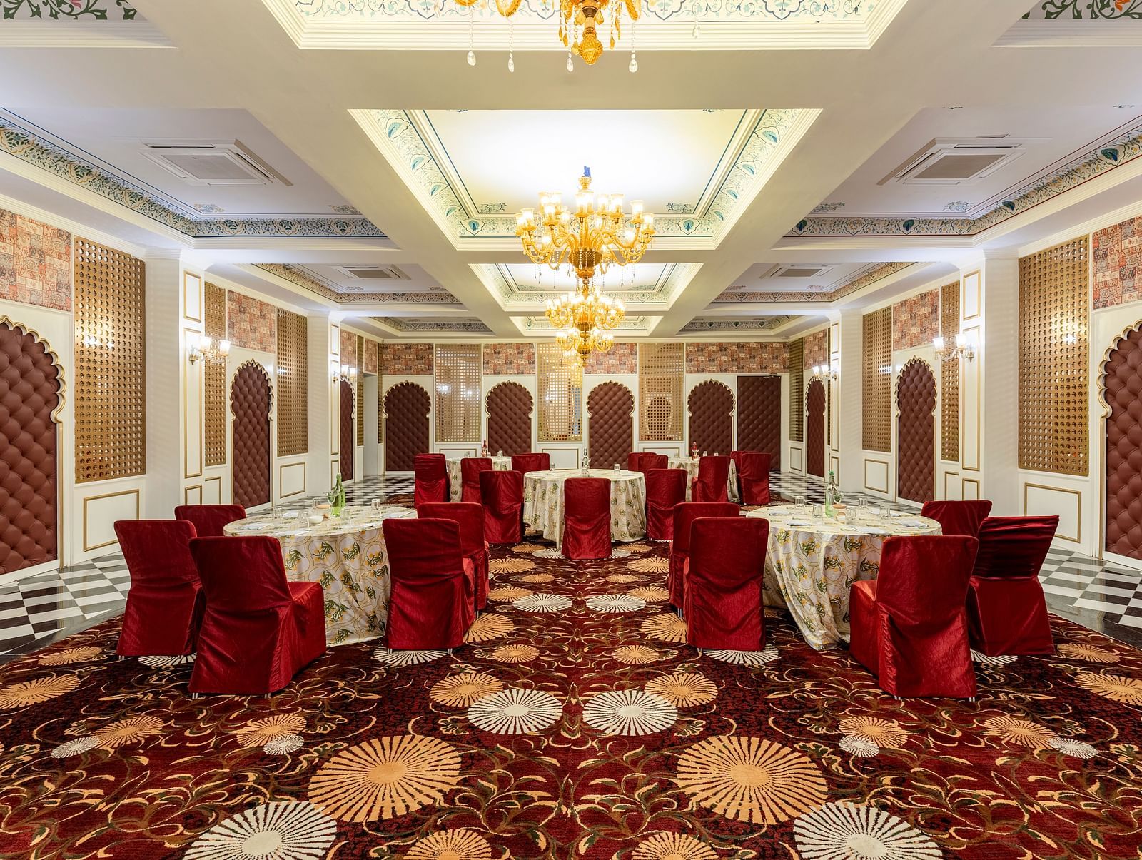 Luxurious banquet hall with red chairs and ornate ceiling at Kesar Bagh Palace.