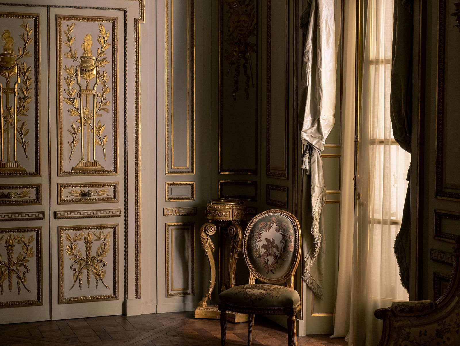 Ornate wall paneling and vintage armchair with royal aesthetics.
