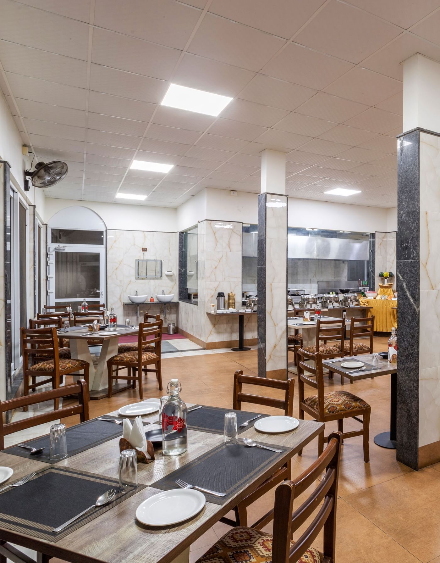 Bright indoor dining area with wooden tables and chairs at Nirantara Resort.