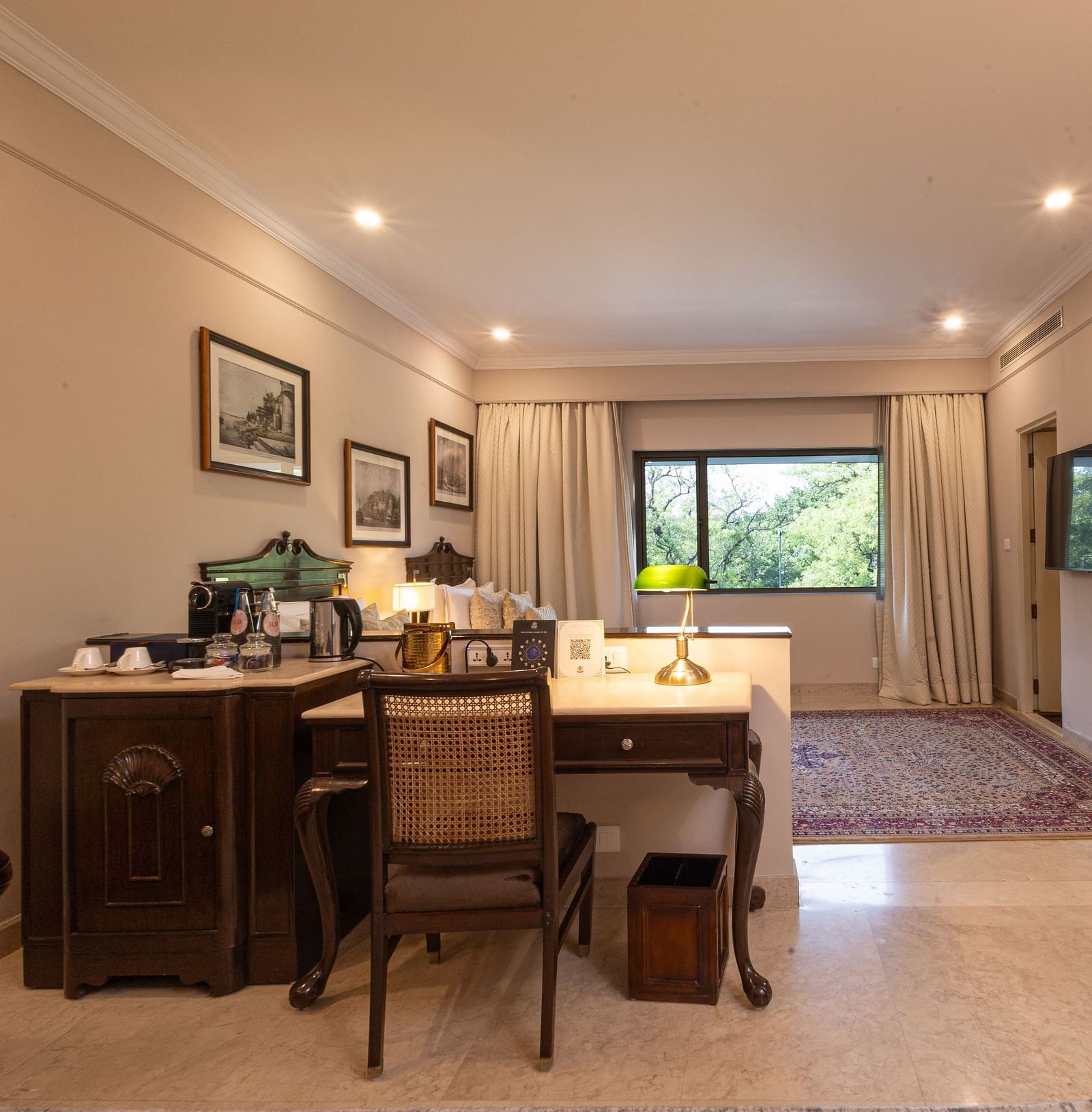 Corner view of the Grand Luxury Twin Bed Room at The Claridges New Delhi, showcasing a spacious layout with a stylish table and chair