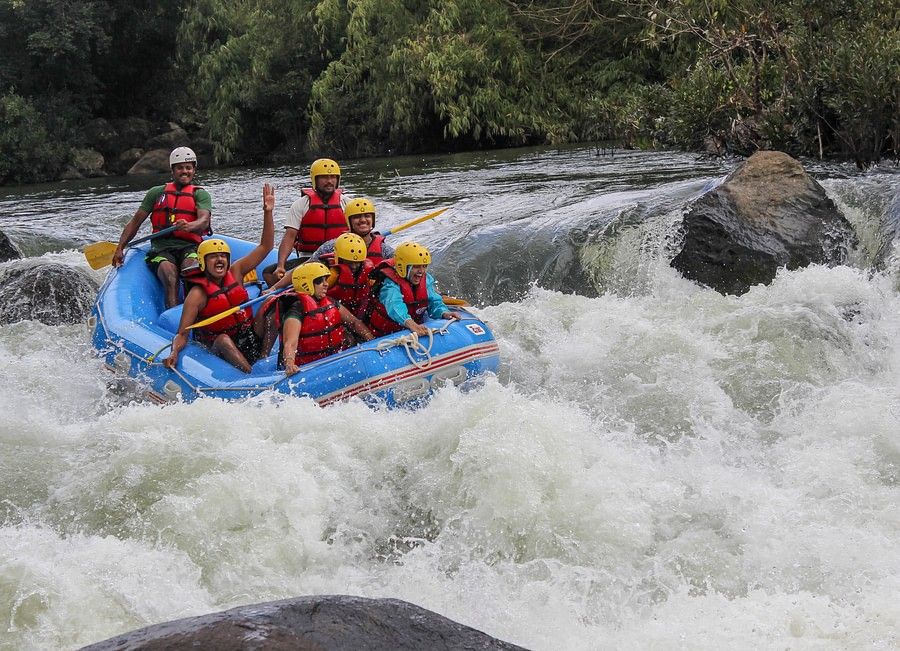  A raft with six people in safety gear navigating through a rough river, showing intense concentration and teamwork in an exhilarating environment.