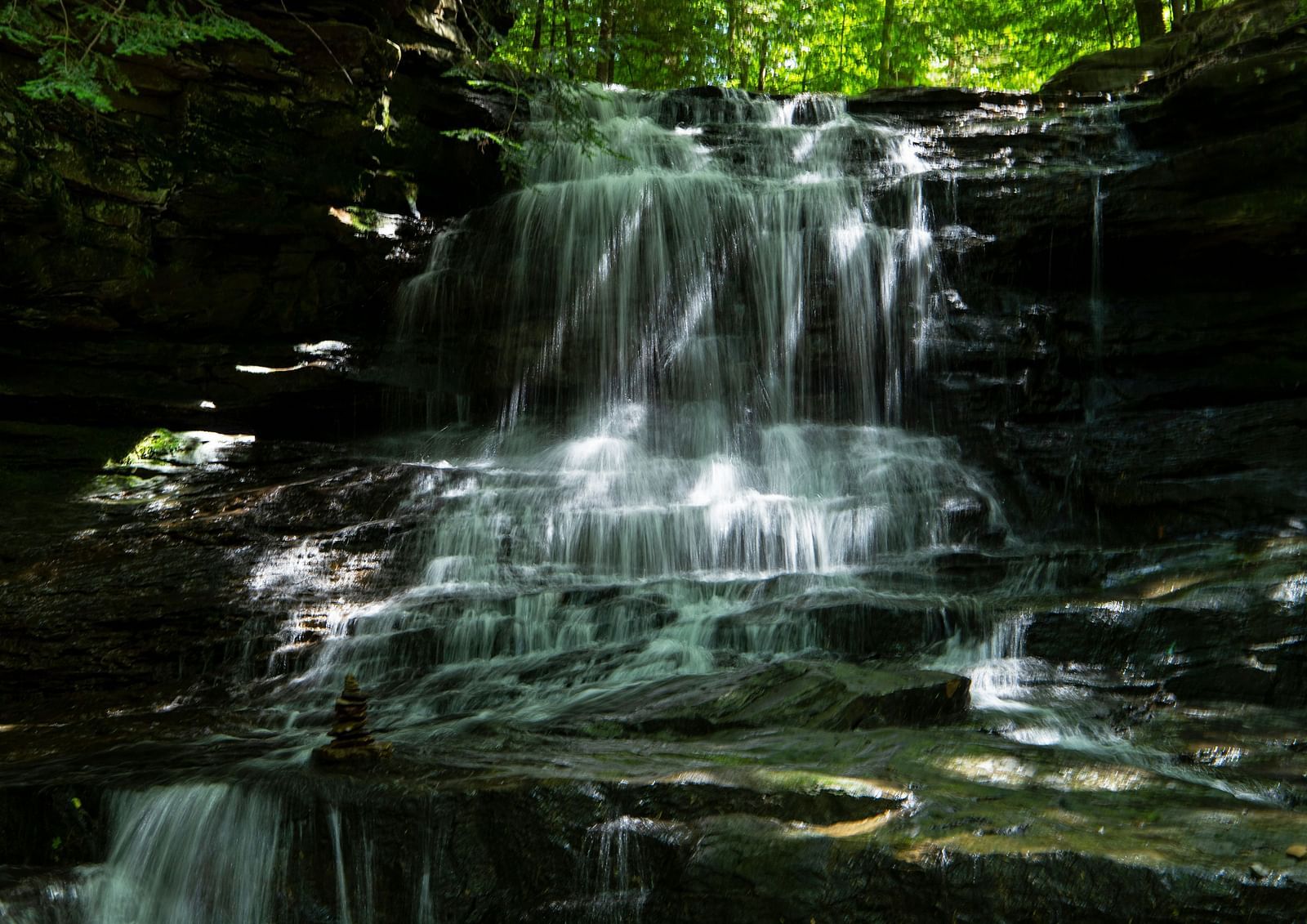 An image of a waterfalls surrounded by lush greenery