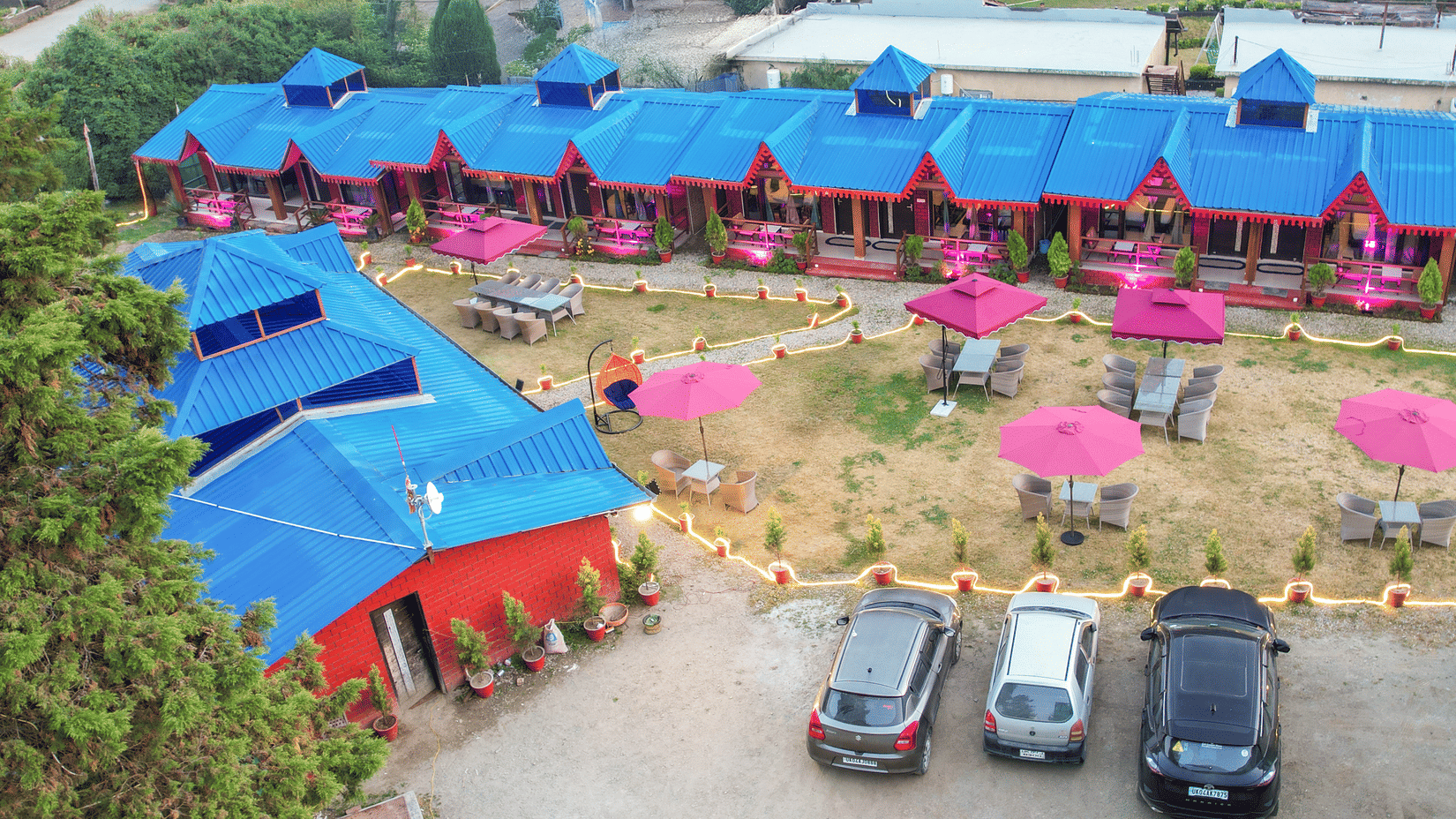 Aerial view of Sol Glow Resort, Nainital showing cars parked in parallel, facing cottages placed side to side.