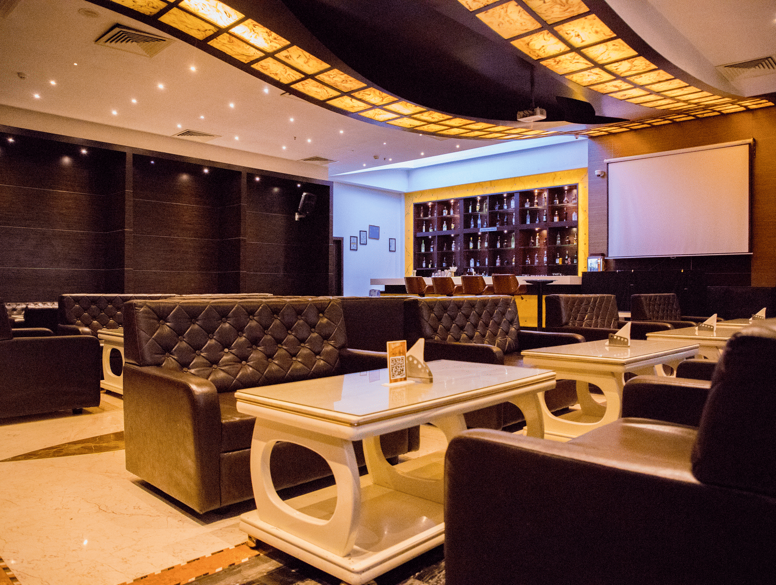 Full view of the dining area at the Benzz Park, Vellore, with warm lighting featuring tufted couch.