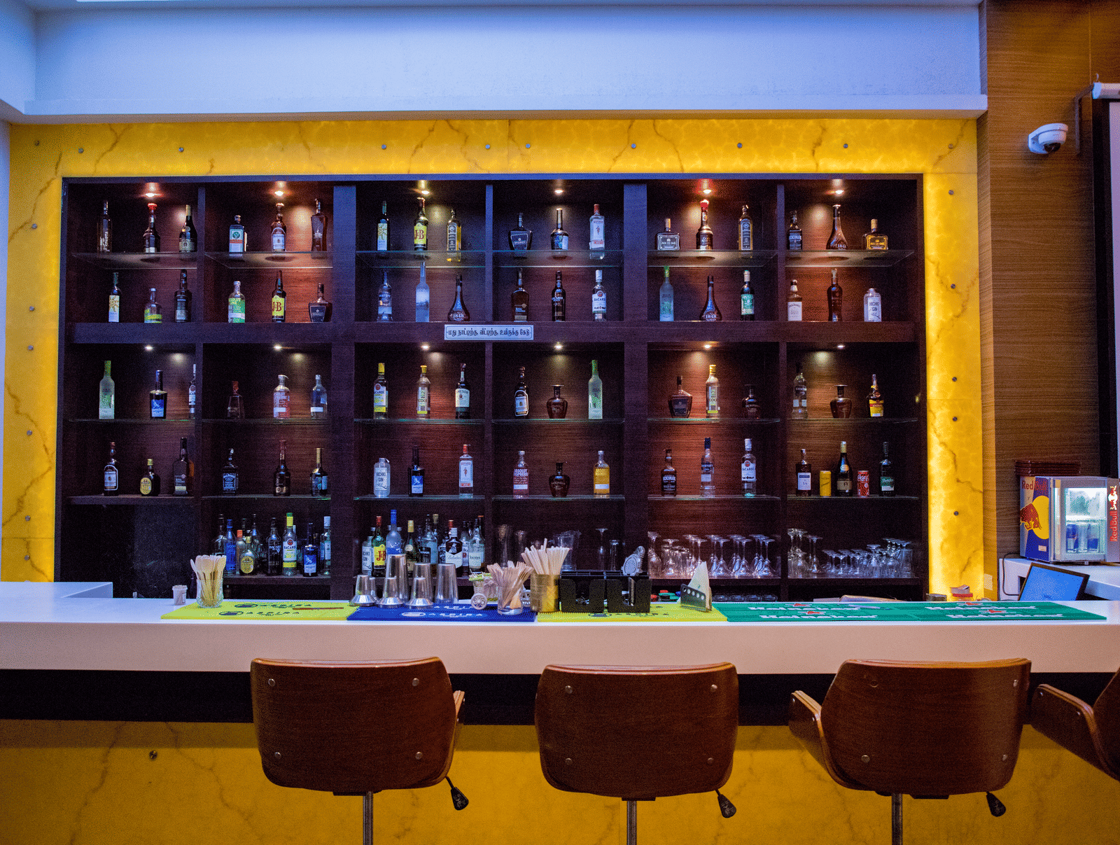 Front view shot of the bar area with an assortment of premium liquor bottles on display behind the bar counter at Benzz Park, Vellore.