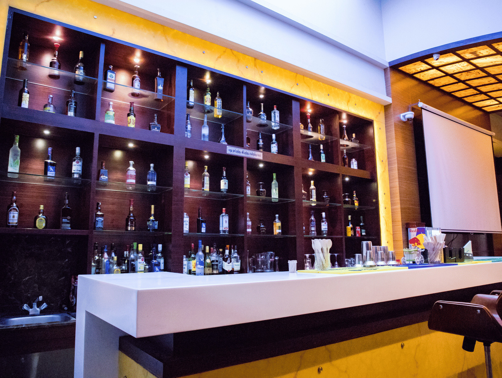 Side view of the bar featuring the bar counter and a display cabinet stacked with various liquor bottles on display at Benzz Park, Vellore.