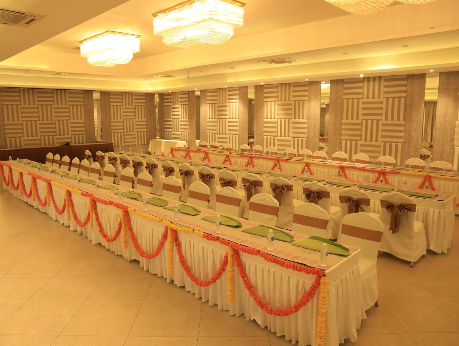 A spacious indoor hall set up with long tables and chairs, adorned with sashes and colourful runners, ready for a large event or conference | Grande Pavillion | Grand Bay Resort and Spa