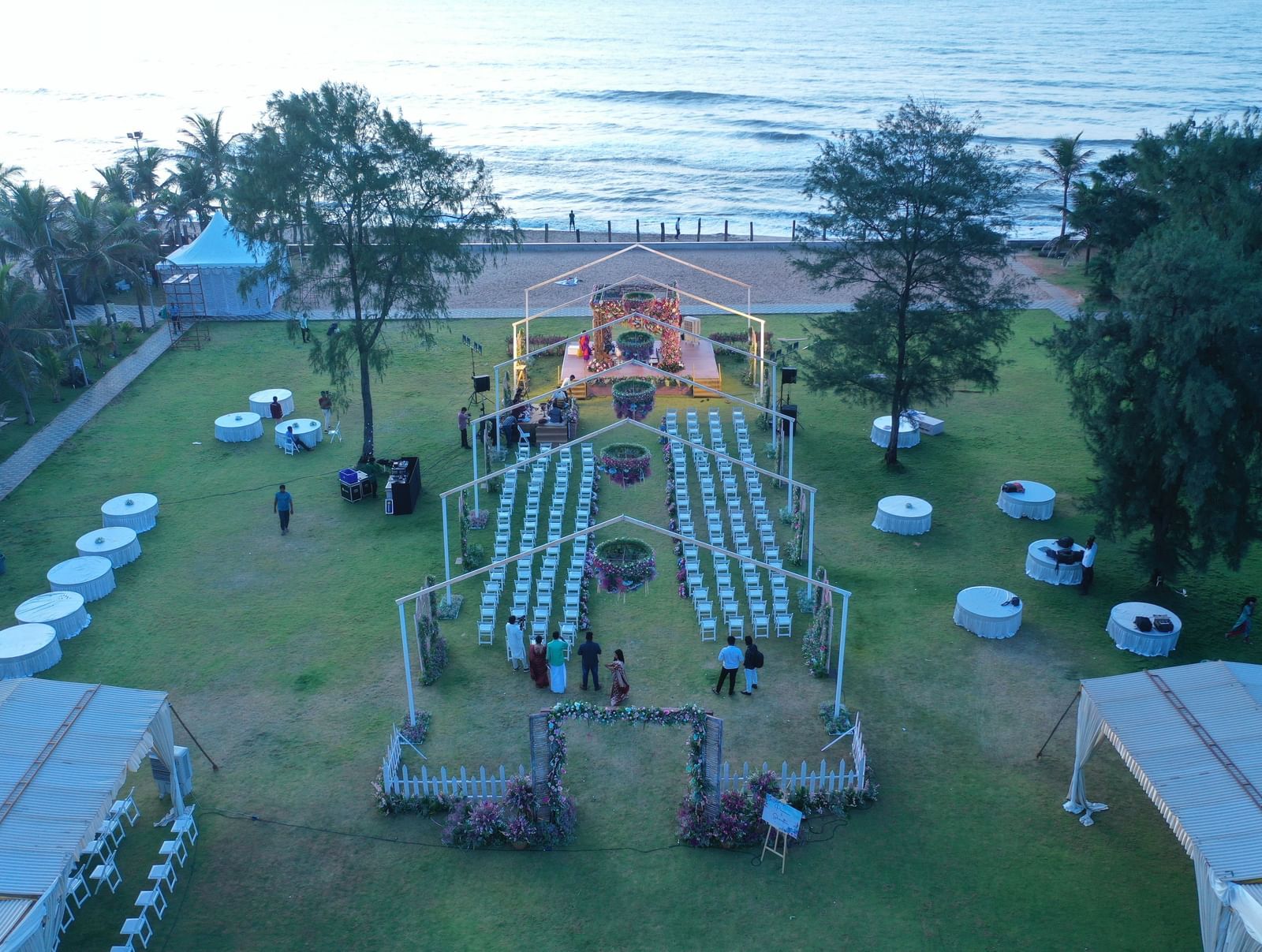 An aerial view of an outdoor event space on a lawn by the ocean, with numerous chairs and small tables arranged for a gathering | Horizon | Grand Bay Resort and Spa