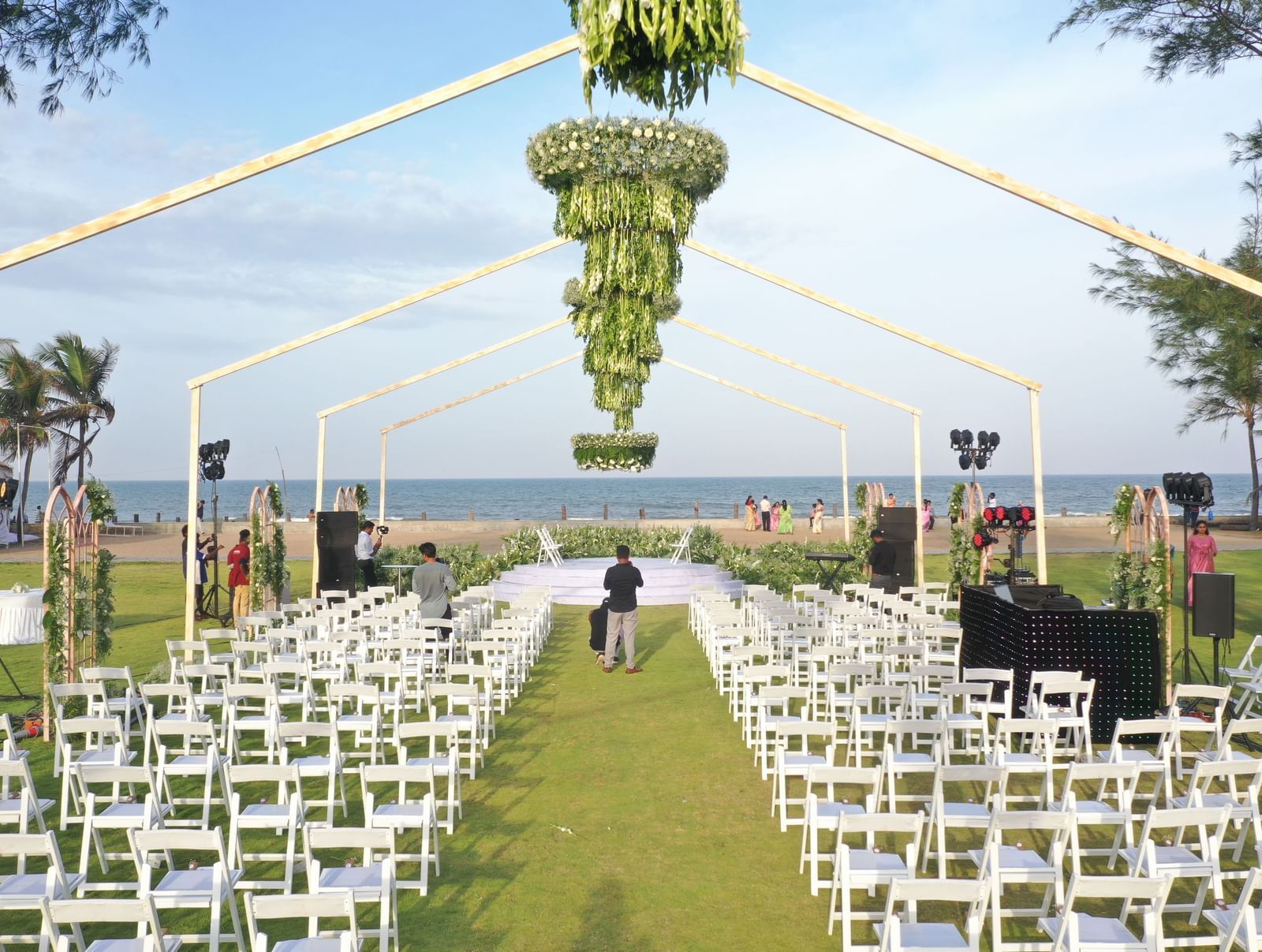 An outdoor wedding aisle with white chairs lined up and a tall, decorative archway at the end, leading towards the ocean | Horizon | Grand Bay Resort and Spa