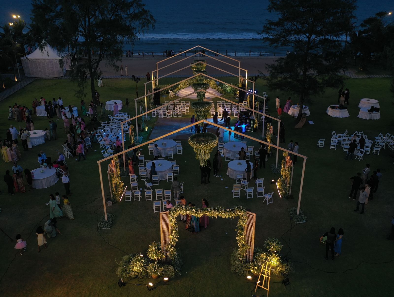 An aerial view of a large outdoor event or wedding reception under a tent on a lawn at dusk, with lights illuminating the space | Horizon | Grand Bay Resort and Spa