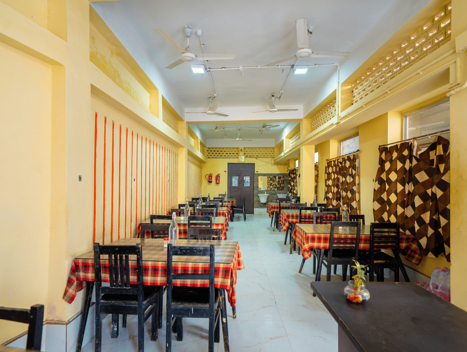 Hotel dining hall showing multiple tables set up under overhead ceiling fans - Hotel Dolphin Puri