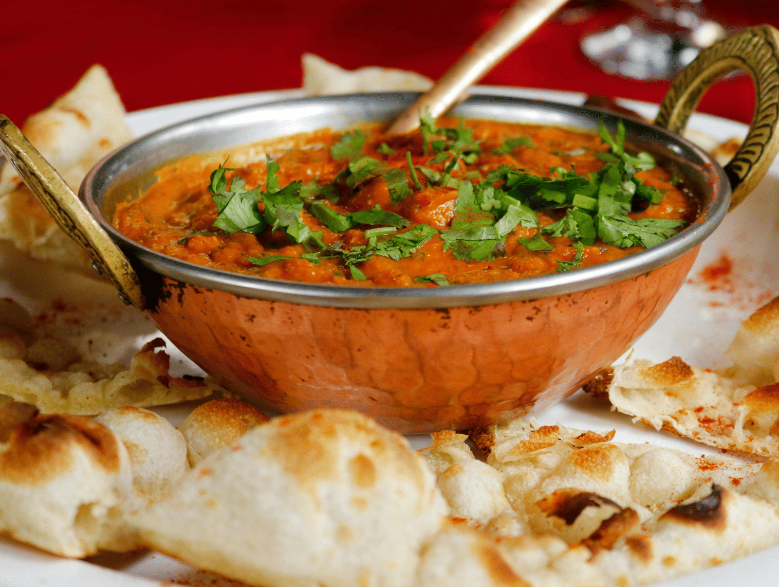An Indian flatbread on which a bowl of curry has been placed.
