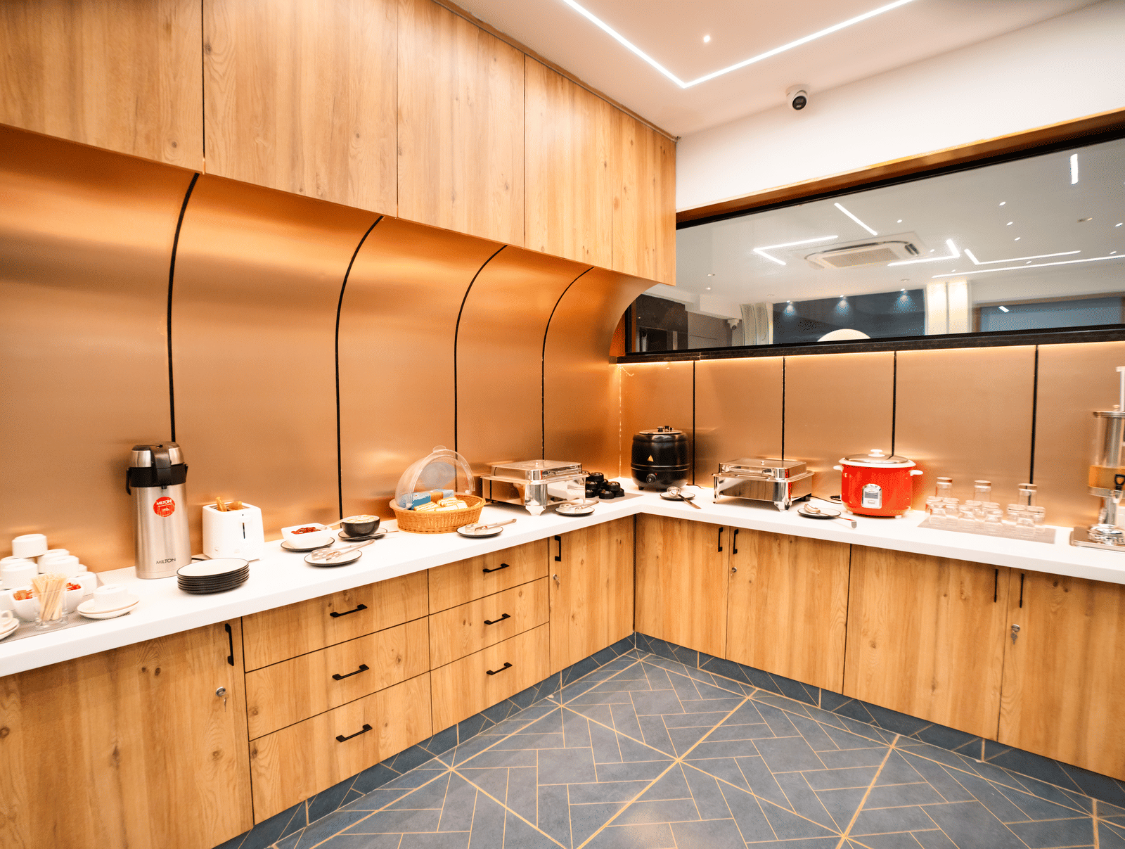 Dining area with buffet setup on an L-shaped counter featuring various dishes and cutlery at Sunrise Business Hotel, Hyderabad.