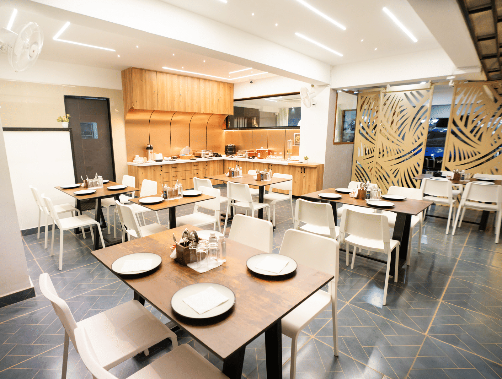 Restaurant seating area with tables and chairs set for dining at Sunrise Business Hotel, Hyderabad.