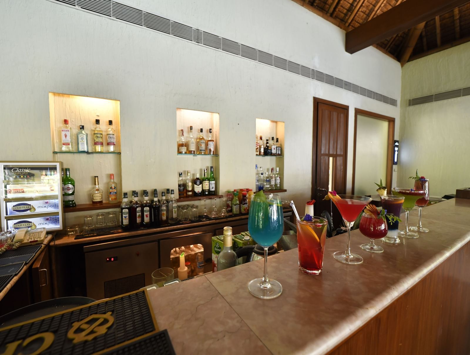 A bar counter with drinks and bottles neatly arranged, at Vedic Village Spa Resort.