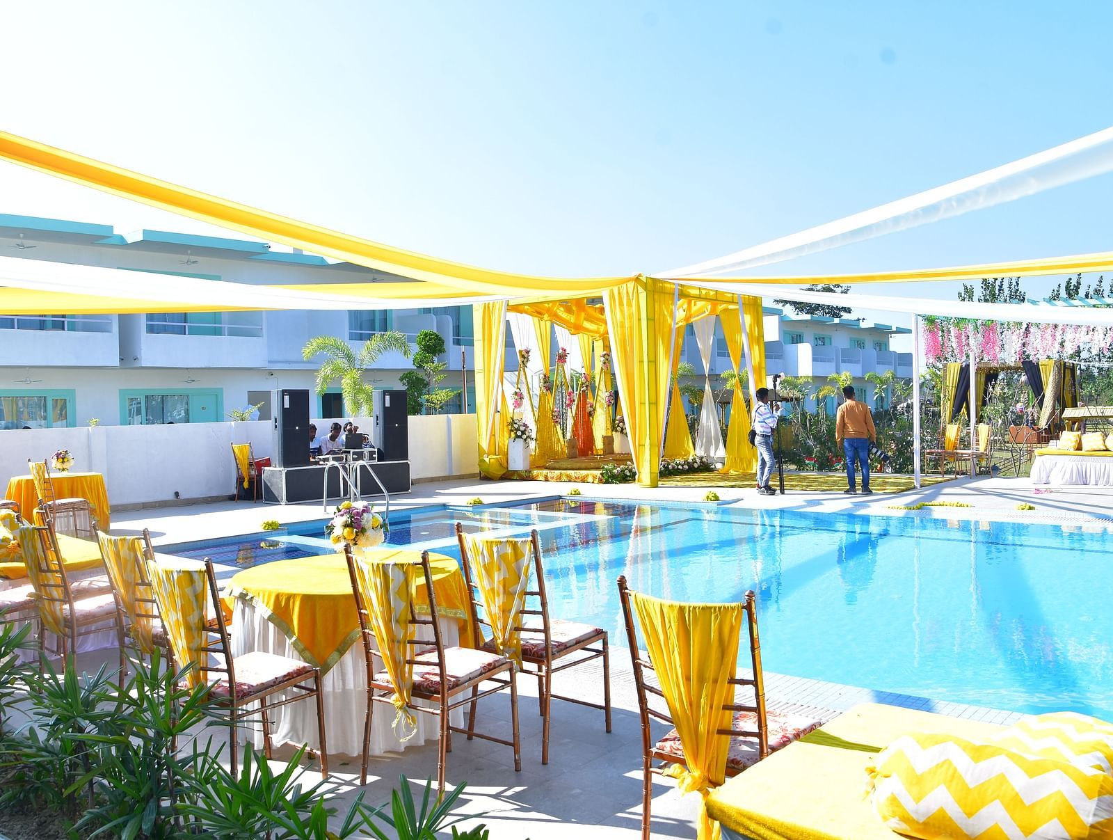 Poolside wedding seating arrangement with bright yellow drapery at Vedikant Resorts The Mallard Corbett.