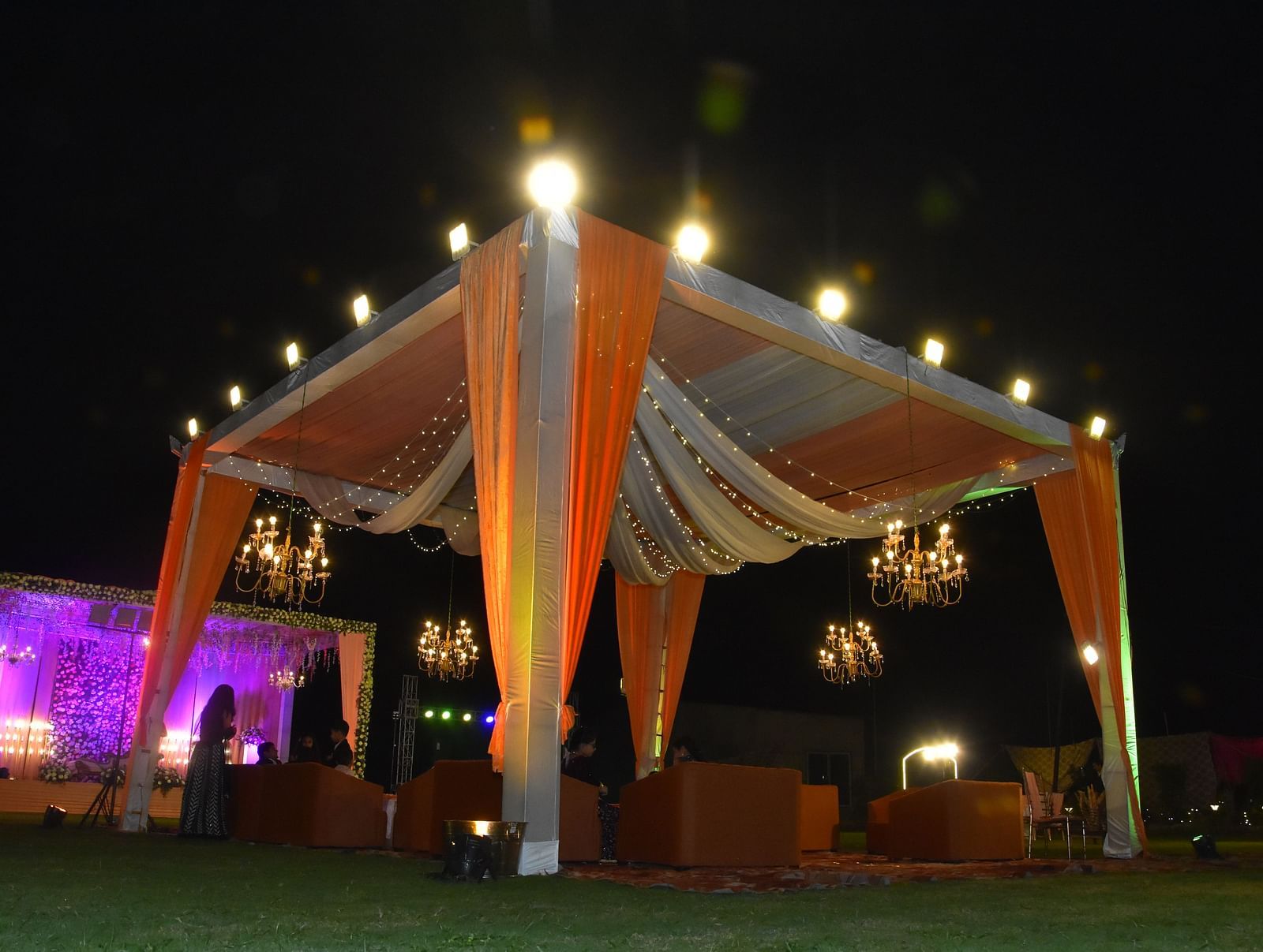 Outdoor event canopy with draped lights and seating at Vedikant Hotels & Resorts with night sky in the background.