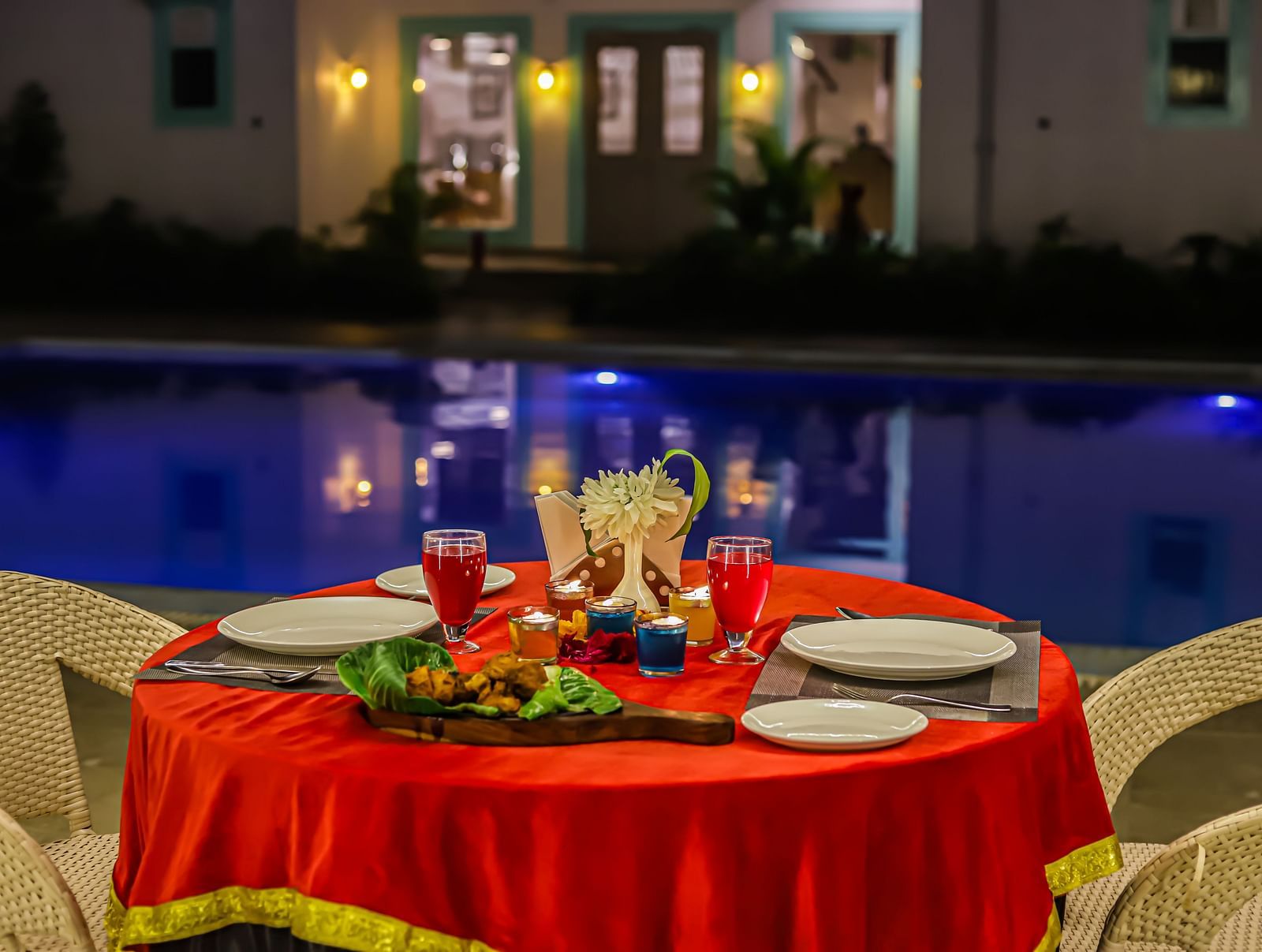 A poolside dining setup at Vedikant Resorts The Mallard Corbett at night features a decorated table and chairs.