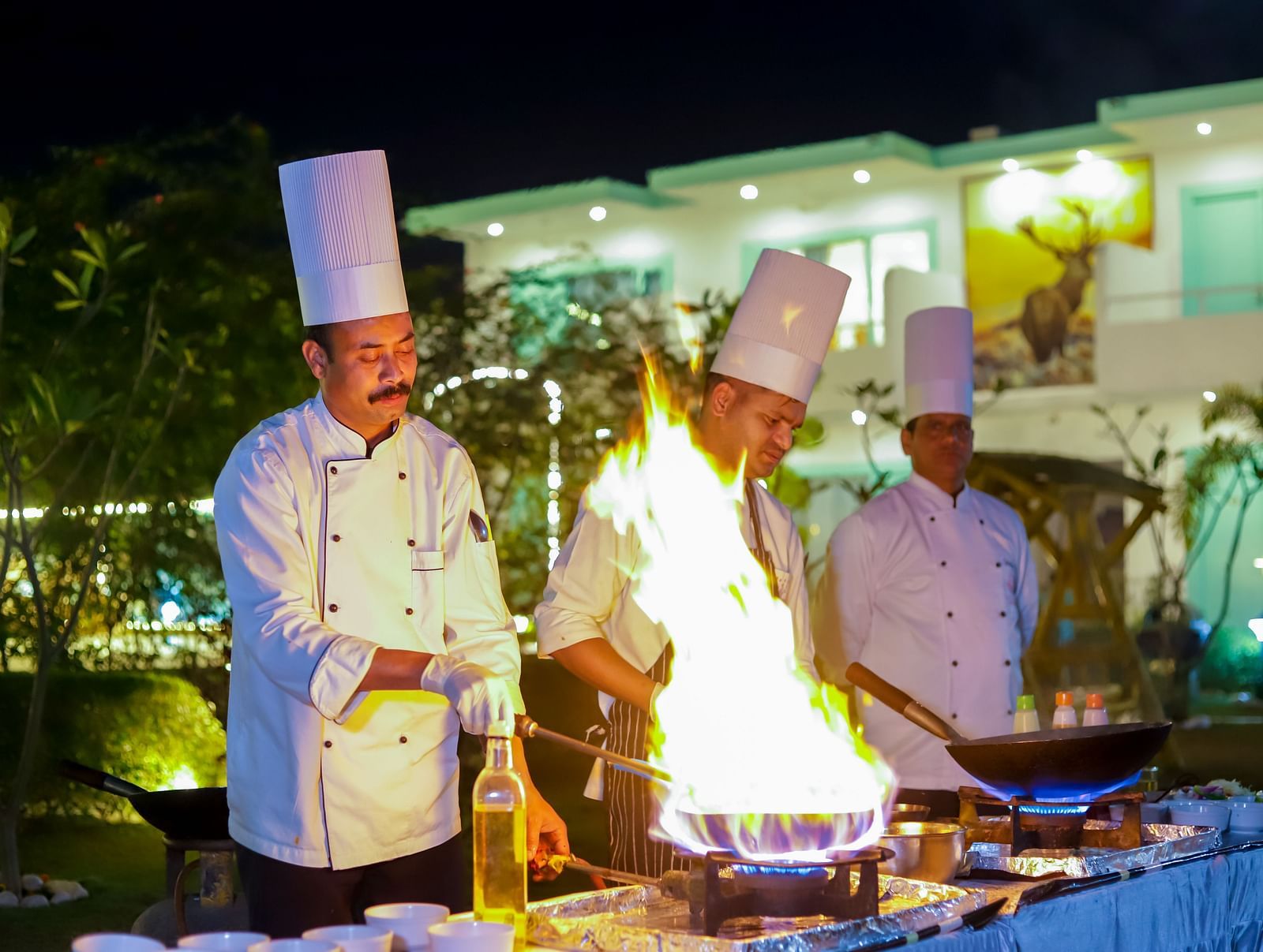 Vedikant Resorts The Mallard Corbett chefs performing a live cooking session with flames rising from the grill.