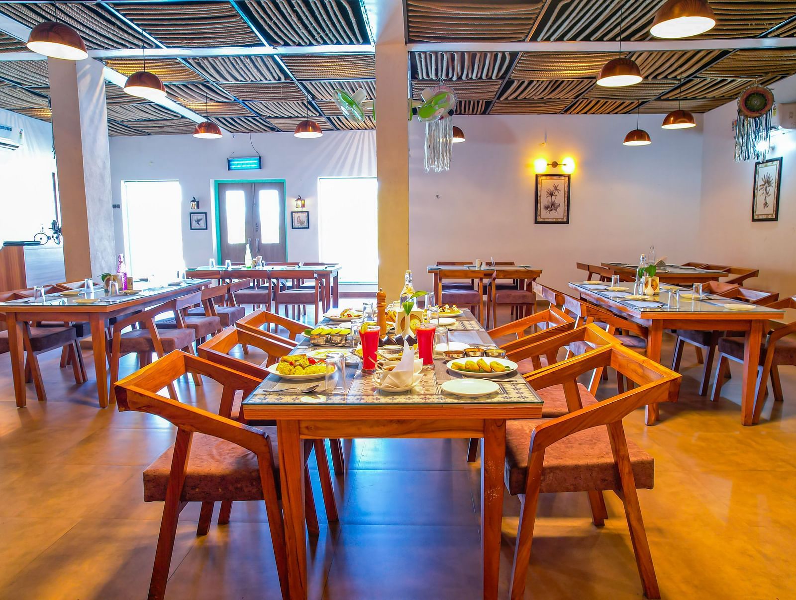 A dining area at Vedikant Resorts The Mallard Corbett displays wooden tables and chairs in a comfortable setting.