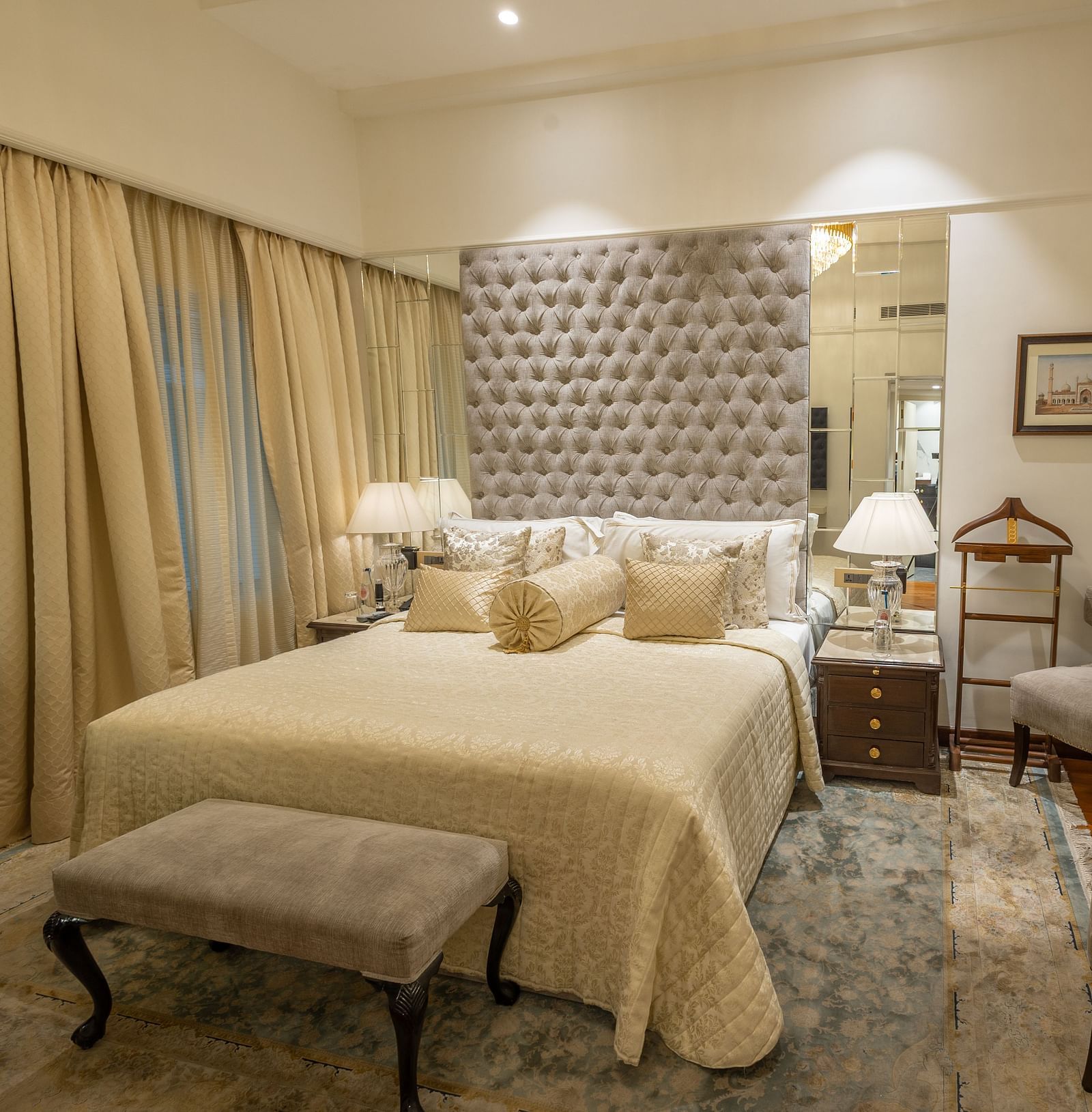 Superior Room at The Claridges New Delhi, featuring a cosy bed with bedside lights and two chairs arranged in the corner