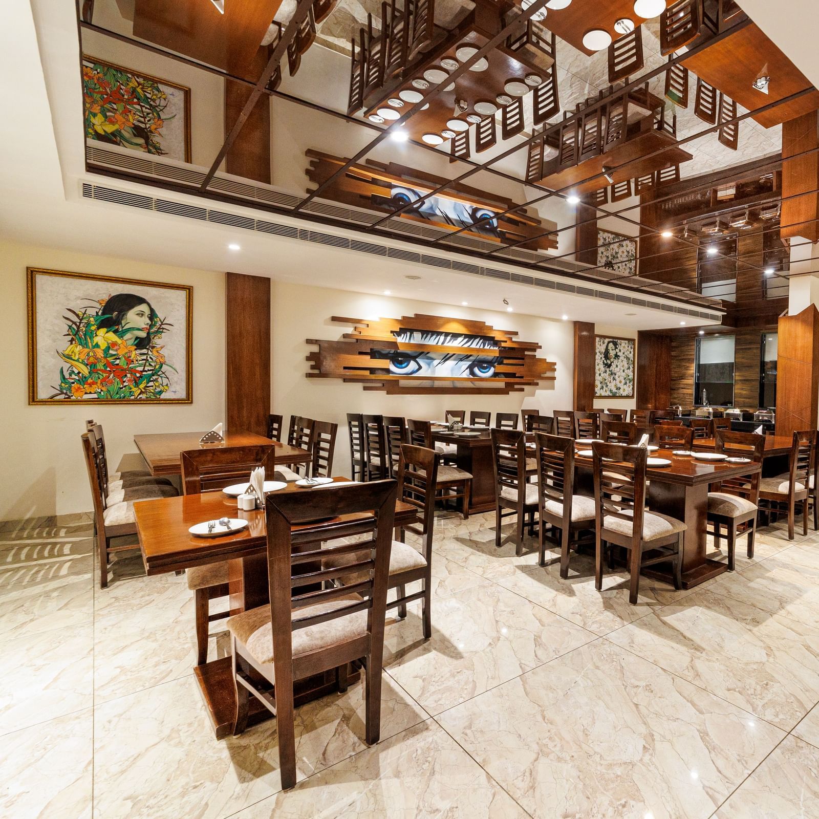 Restaurant at Inde Reva Resorts Rishhikesh featuring wooden furniture, open ceiling design, framed art, and tiled flooring.