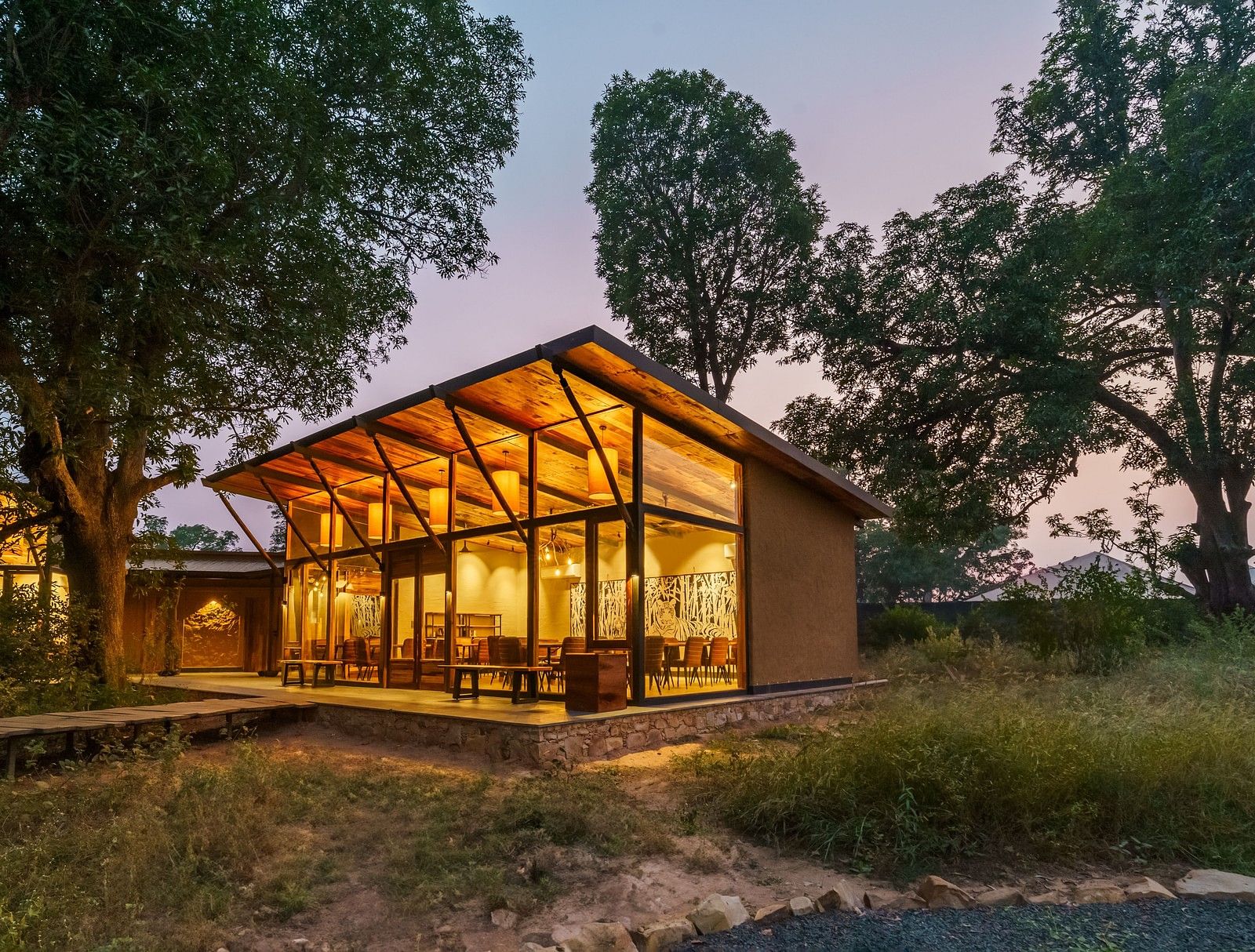 Facade view of a well lit cottage surrounded by trees at Trees N Tigers, Tadoba.