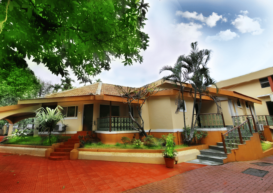 An overview of the exterior facade of the Zara's Resort, Khandala, surrounded by greenery and blue sky in the background.