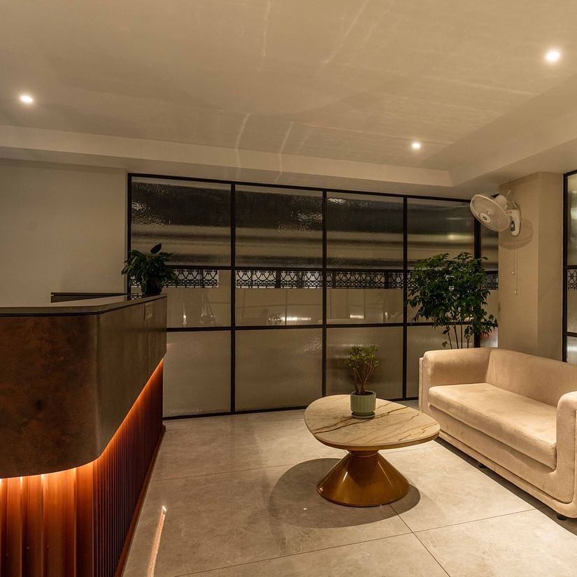 A reception area with a comfortable sofa in front of the reception desk - Court 11, Kochi