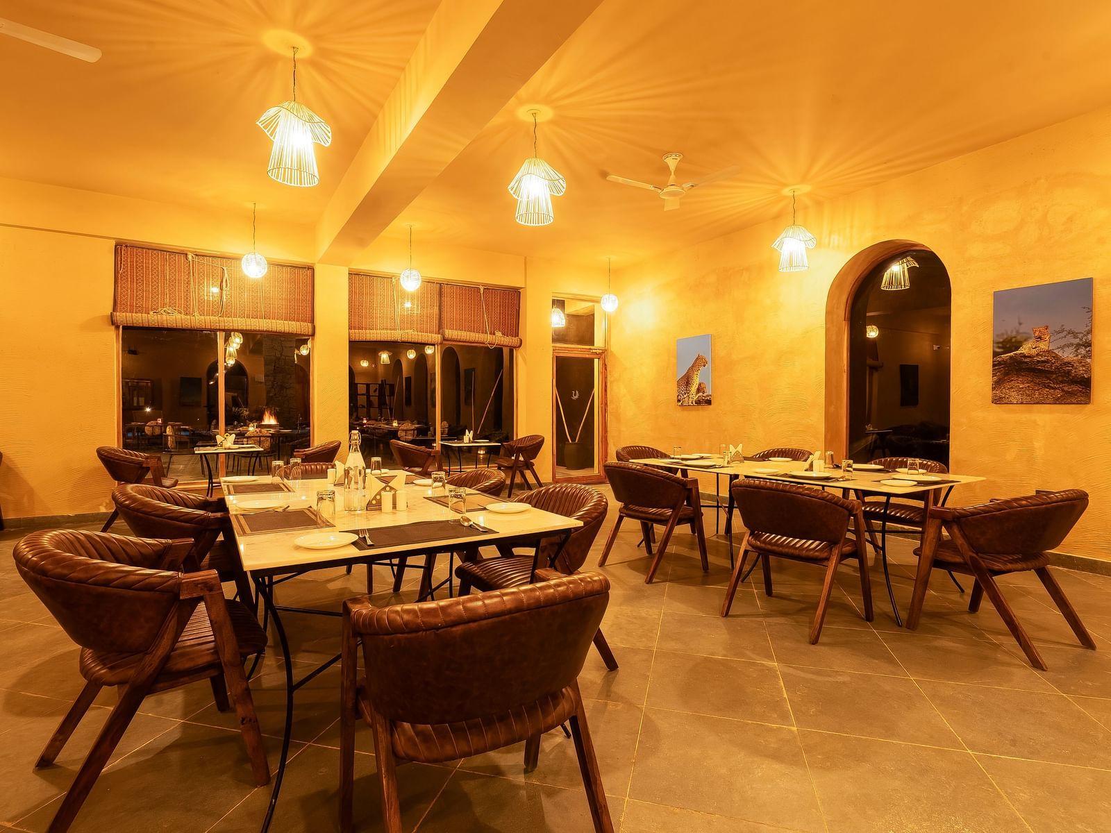 An image of L cave restaurant featuring ceiling lights, dining table and chairs in boho theme and there is also an open entrance - Kurja Jawai
