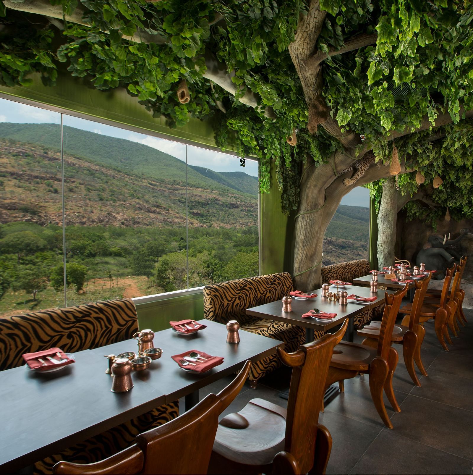 Seating arrangements in front a floor to ceiling glass windows at Gufha Restaurant -Hotel Pai Viceroy Tirupathi