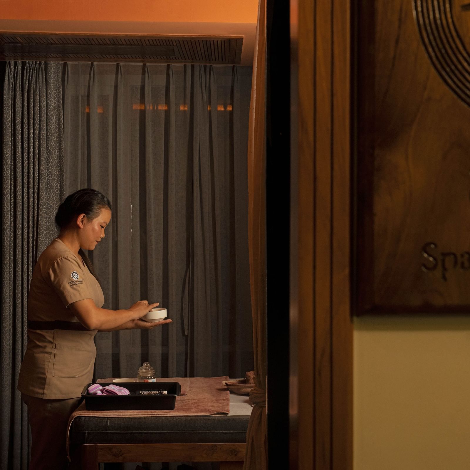 Image of Ayur Spa at Coral Reef Hotel and Spa in Port Blair featuring a masseuse preparing essentials for spa holding a little bowl