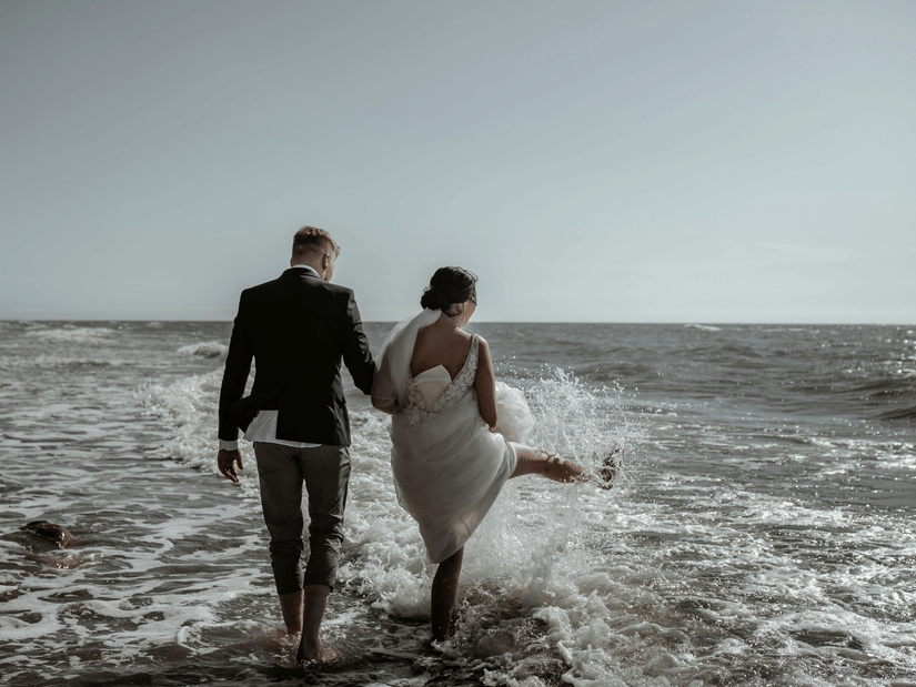 Couple holding hands while walking along the beach during a moody sunset