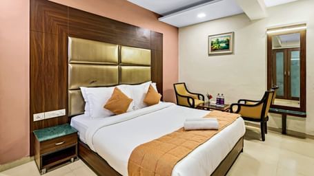 A well-lit executive room in Krushnai Resort featuring a double bed with white lnen and yellow runner.