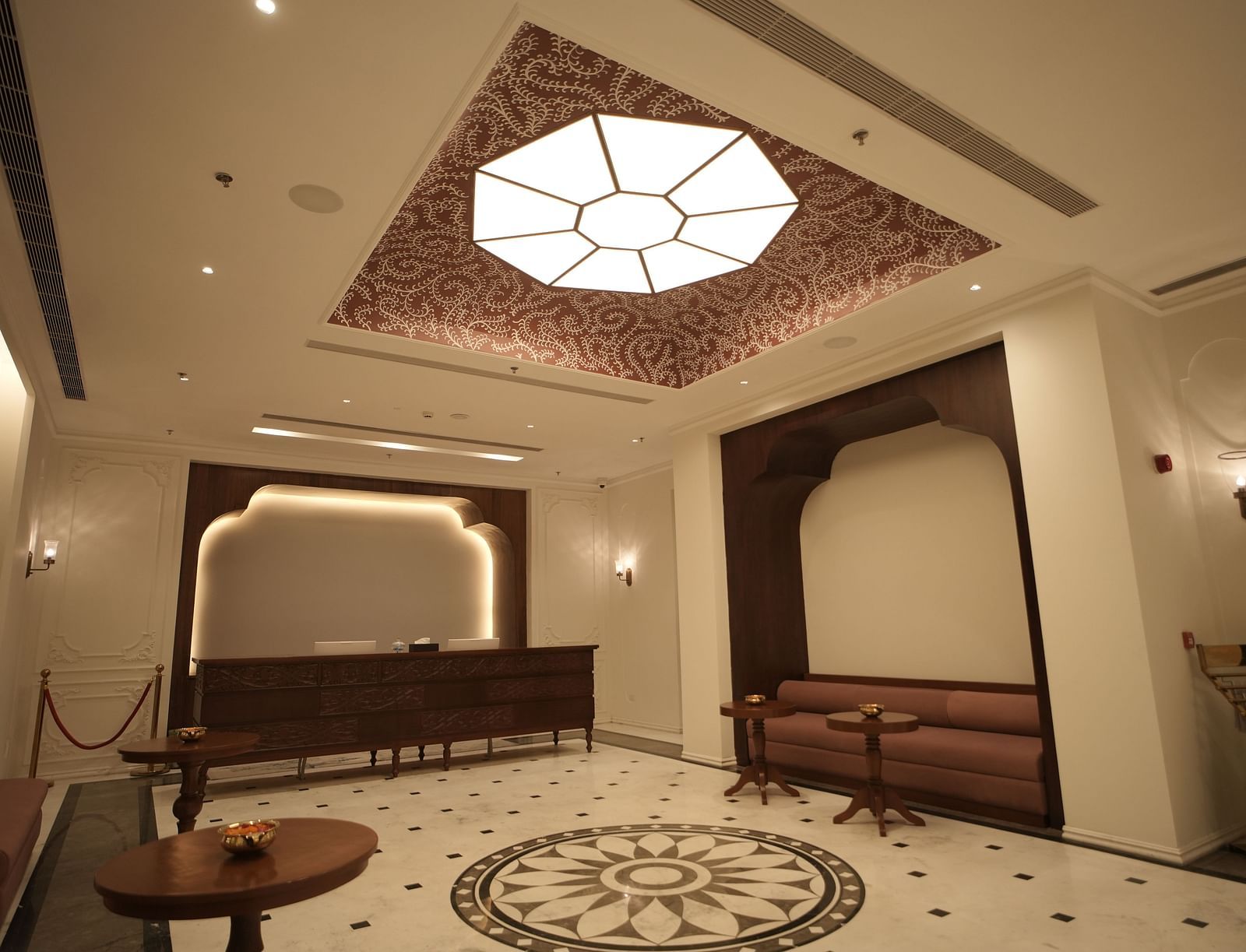 An expansive lobby area at Bhagirathi by RDB Atishay with an atrium on the ceiling featuring intricate patterns painted on it.