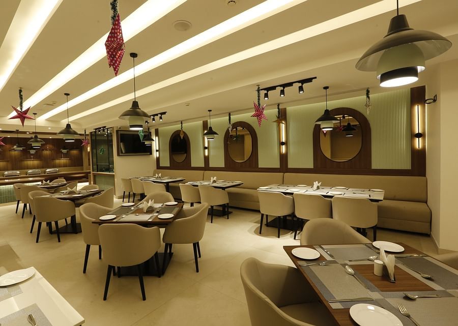 A banner of a restaurant featuring chairs and tables across the room and there are ceiling lights hanging from top - Tulip Inn, Zirakpur