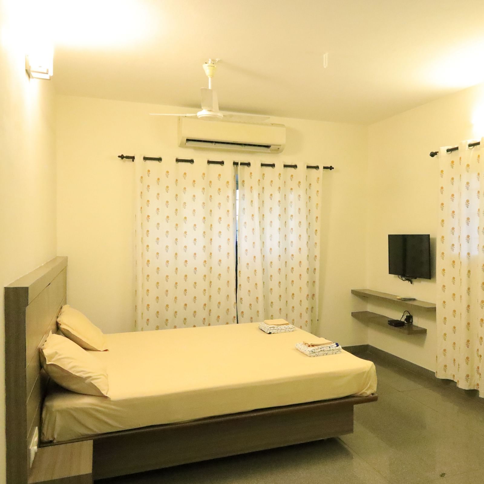A room at Wyt Hotels Transit Nest, Madurai featuring a double bed, curtains covering windows, and a flat TV screen.