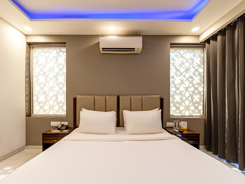 A hotel room with ambient lighting and a wall-mounted split A/C at Hotel Bawa, Gurgaon.