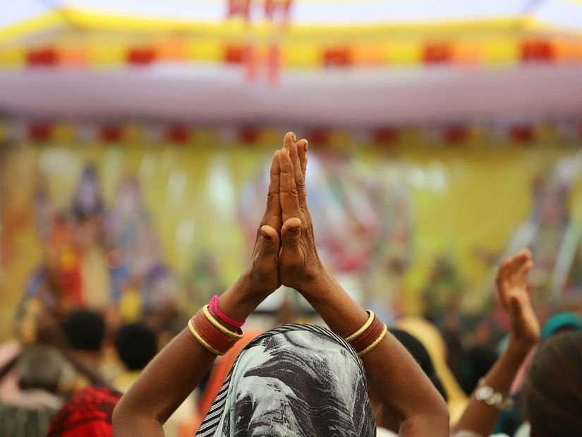 Devotees raising hands in prayer during a vibrant temple festival.