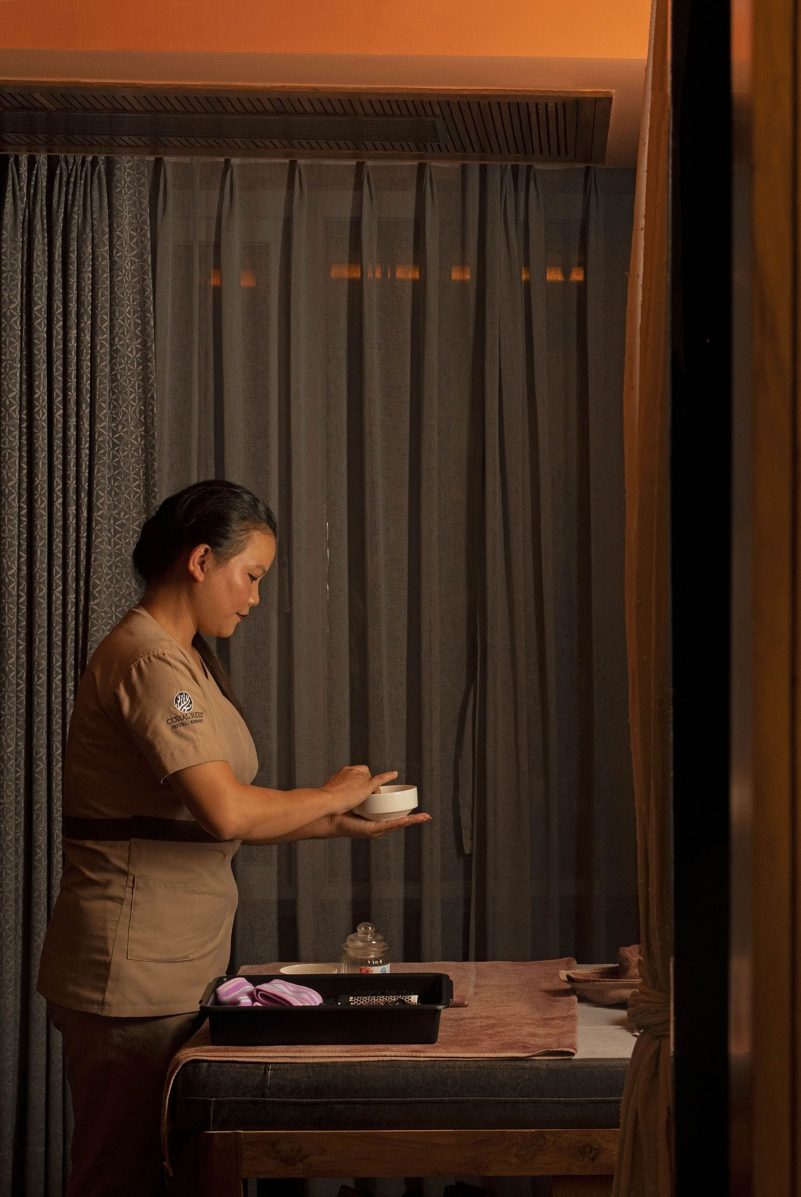 Image of Ayur Spa at Coral Reef Hotel and Spa in Port Blair featuring a masseuse preparing essentials for spa holding a little bowl