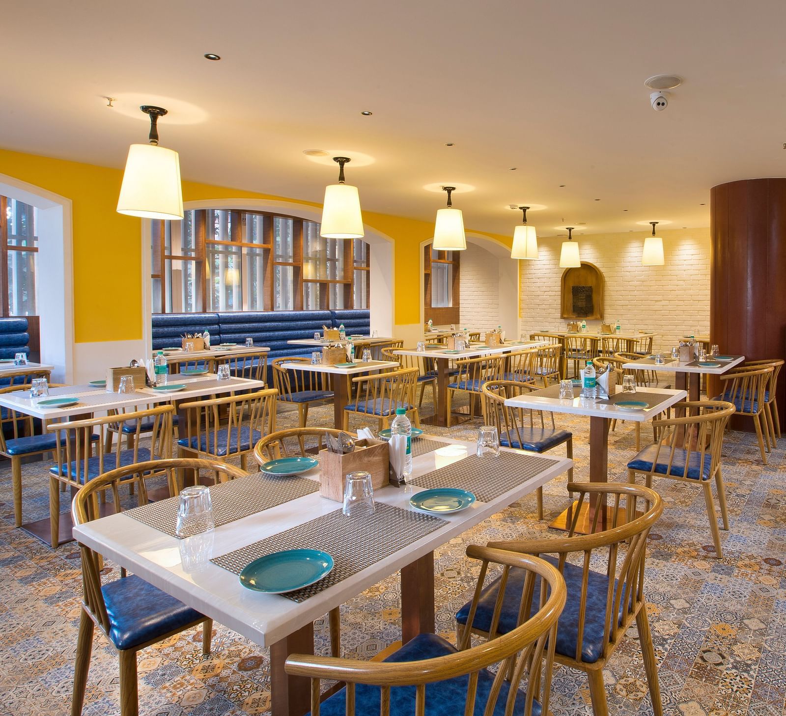 A spacious and brightly lit restaurant with wooden chairs, patterned tile floor and large windows - Hotel Southend by TGI - Bommasandra, Bangalore