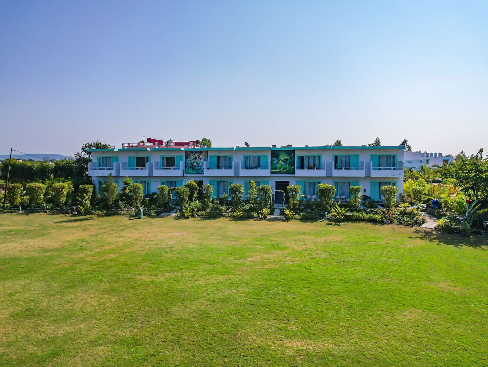 Open lawn at Vedikant Resorts The Mallard Corbett with trimmed grass, resort buildings in the background, and no visible guests.
