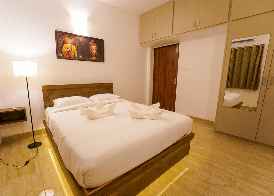 alt-text A cosy double bed with a side lamp and a painting above the bed inside Three Bedroom Villa - La Tamara Luxury, Pondicherry