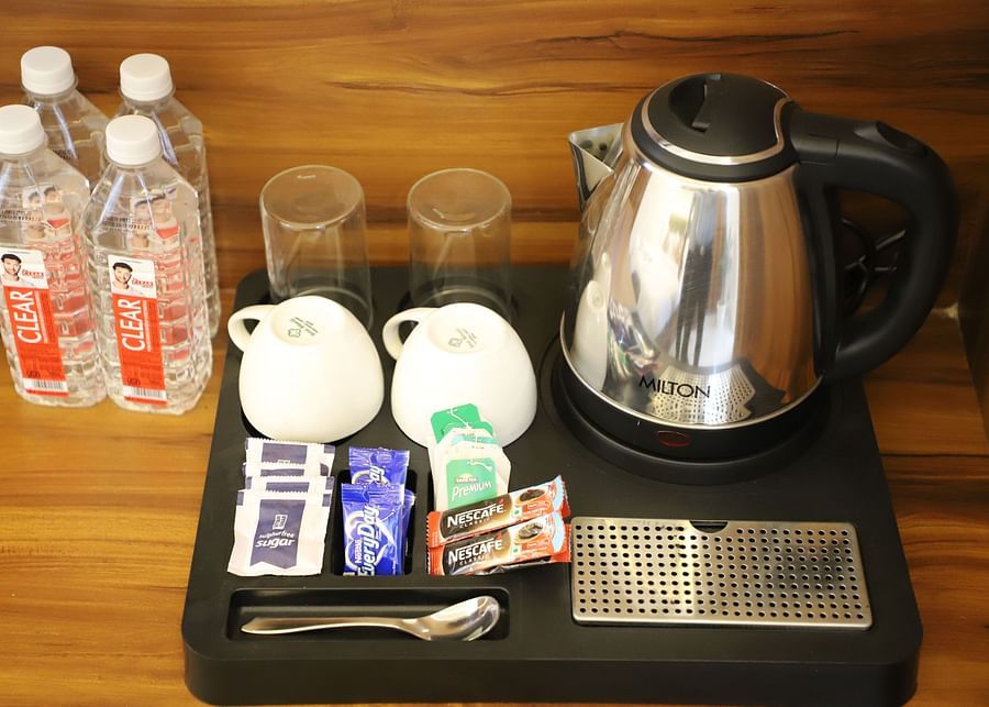 A picture consisting cups a kettle coffee and tea bags and packed water bottles - Opulent Inn by lime tree hotels