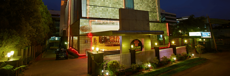 The MGM Mark Whitefield Business Hotel in Bengaluru glows warmly at night, a modern structure with red accents and inviting lights.